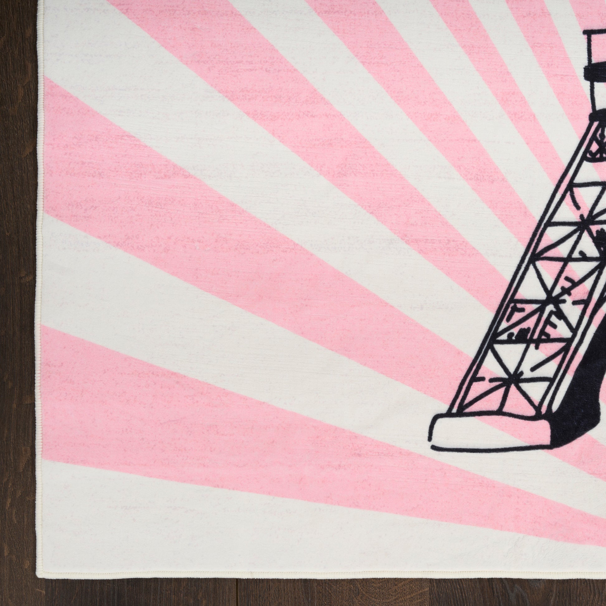 Beige kids' rug with pink sunburst rays and a black line-art Eiffel Tower on the right edge.