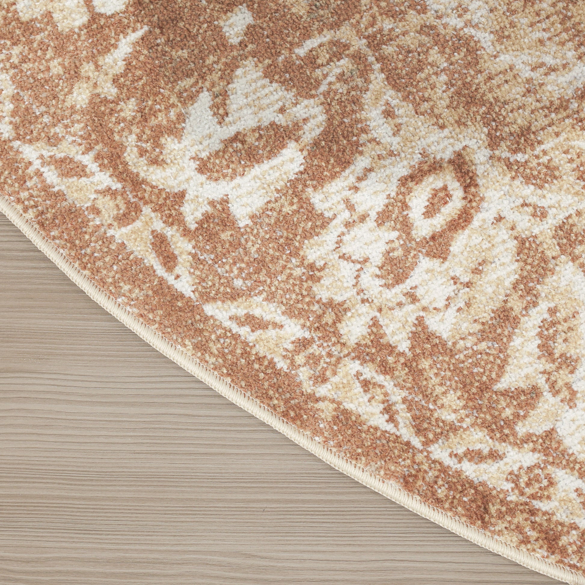 Curved-edge peach and cream patterned area rug with floral motif on light wood floor.