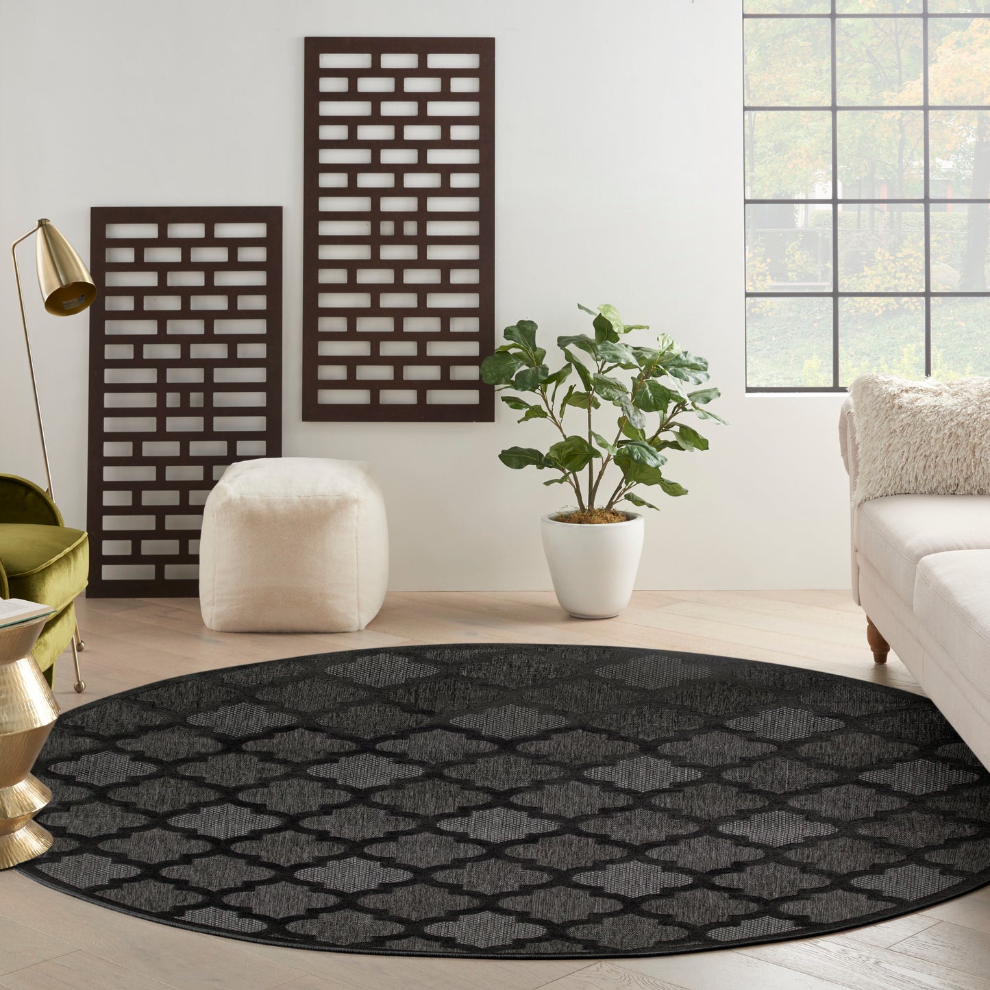 Round black rug with gray lattice pattern in a contemporary living room beside a white sofa and potted greenery.
