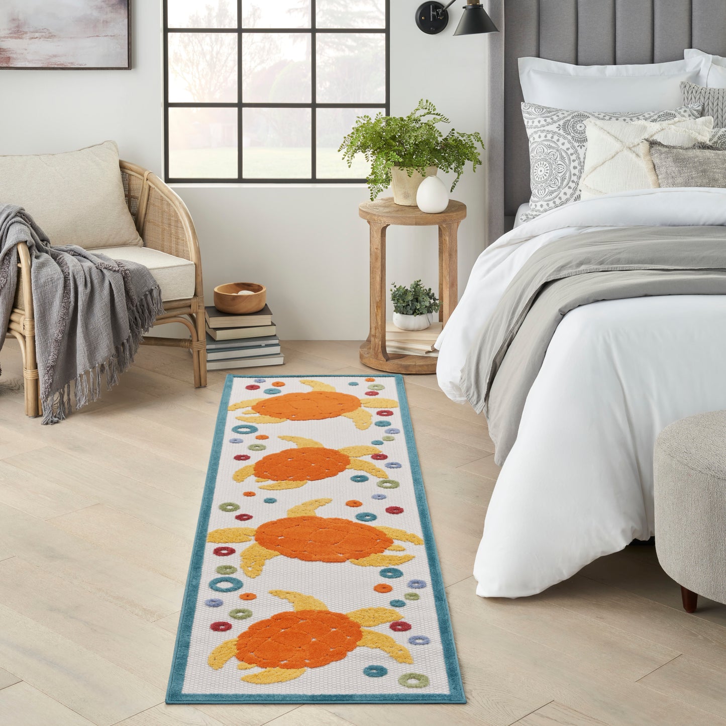 Woven bedside runner with teal border and orange circular motifs with multicolor dots in a light, modern bedroom.