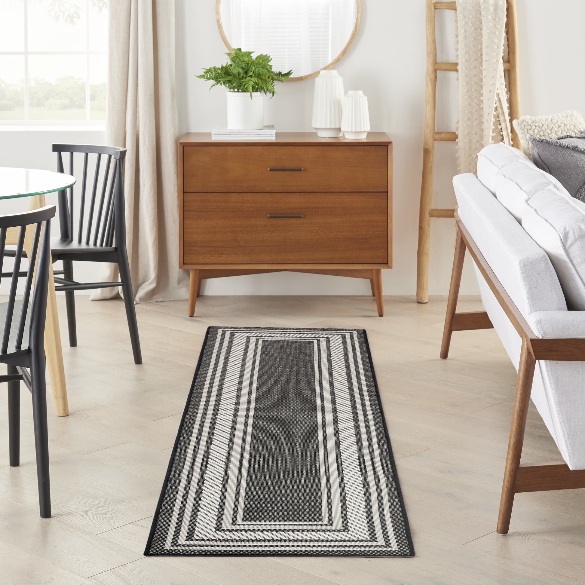 Woven charcoal and light-gray striped rug runner on light wood floor in a modern living room with a mid-century dresser.