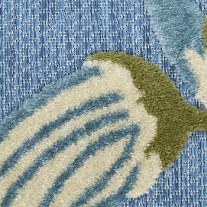 Close-up of a plush fish-pattern rug: cream with blue stripes and olive-green tail on a blue woven surface.