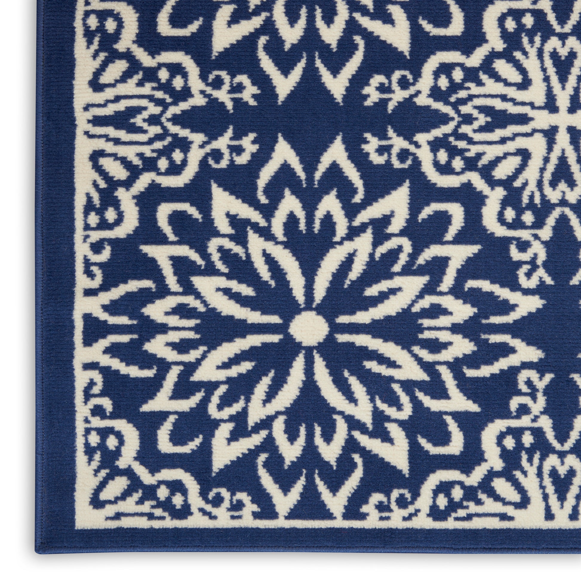 Close-up of a blue area rug with a white intricate starburst pattern and border.