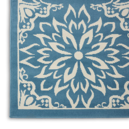 Turquoise textile with white mandala-style floral motif and decorative border; towel or rug.