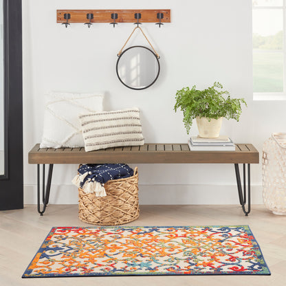 Wood bench with black hairpin legs, striped pillows, round wall mirror, woven basket, potted fern, and vibrant patterned rug.