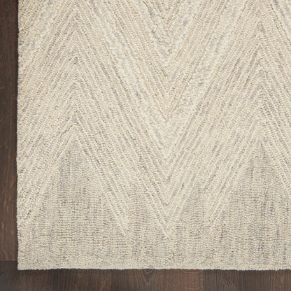 Beige textured rug with raised chevron pattern on dark wood floor.