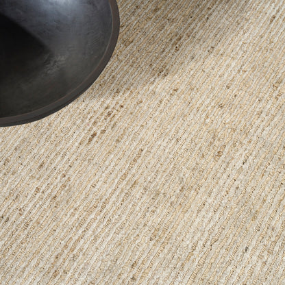 Round dark metal pan edge resting on a beige striped woven rug.