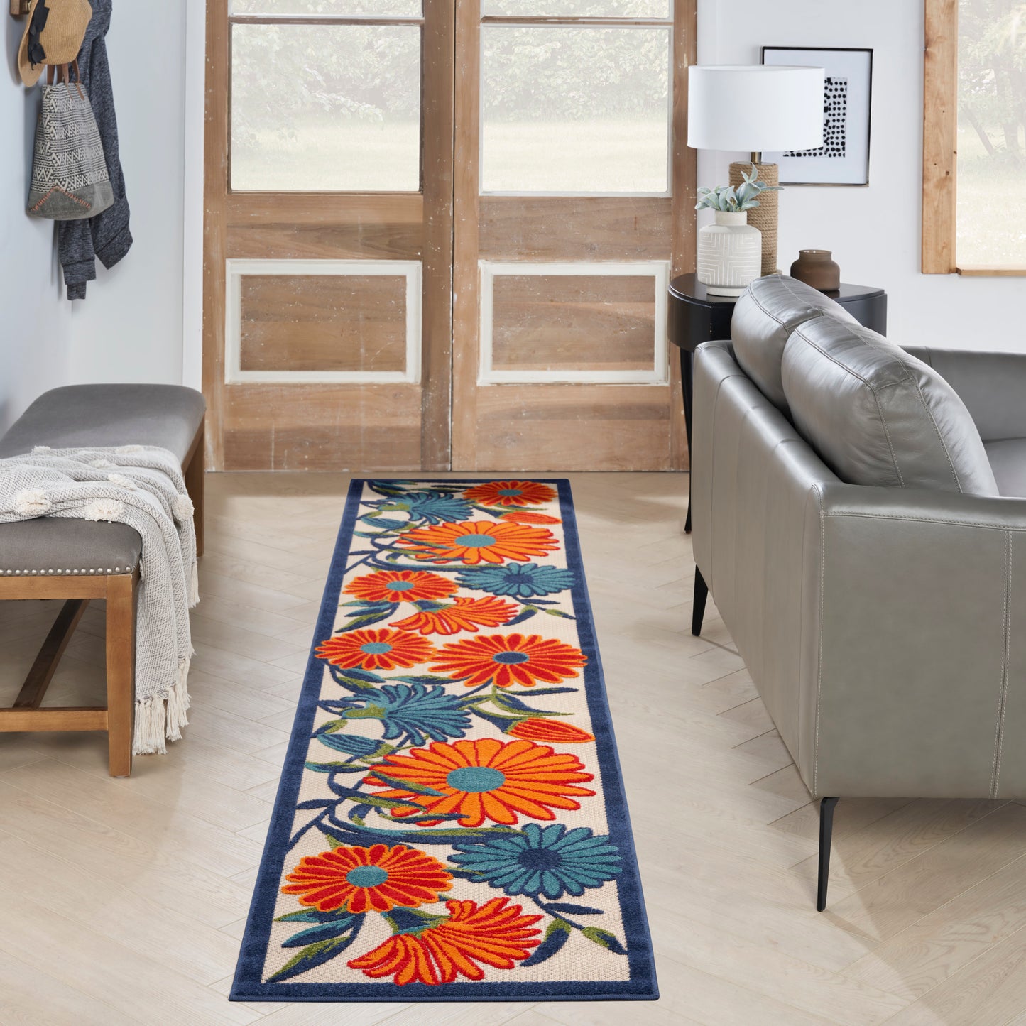 Long floral rug runner for entryway with bright orange flowers and teal leaves on cream, navy border.