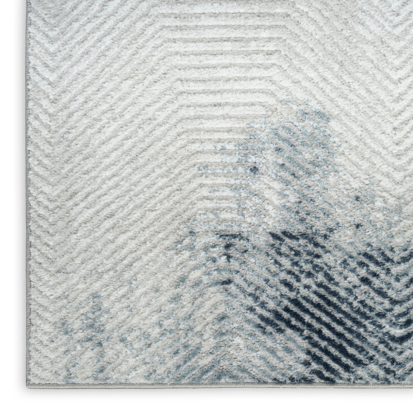 Light gray chevron rug with blue watercolor accents, plush and modern decorative floor cover.