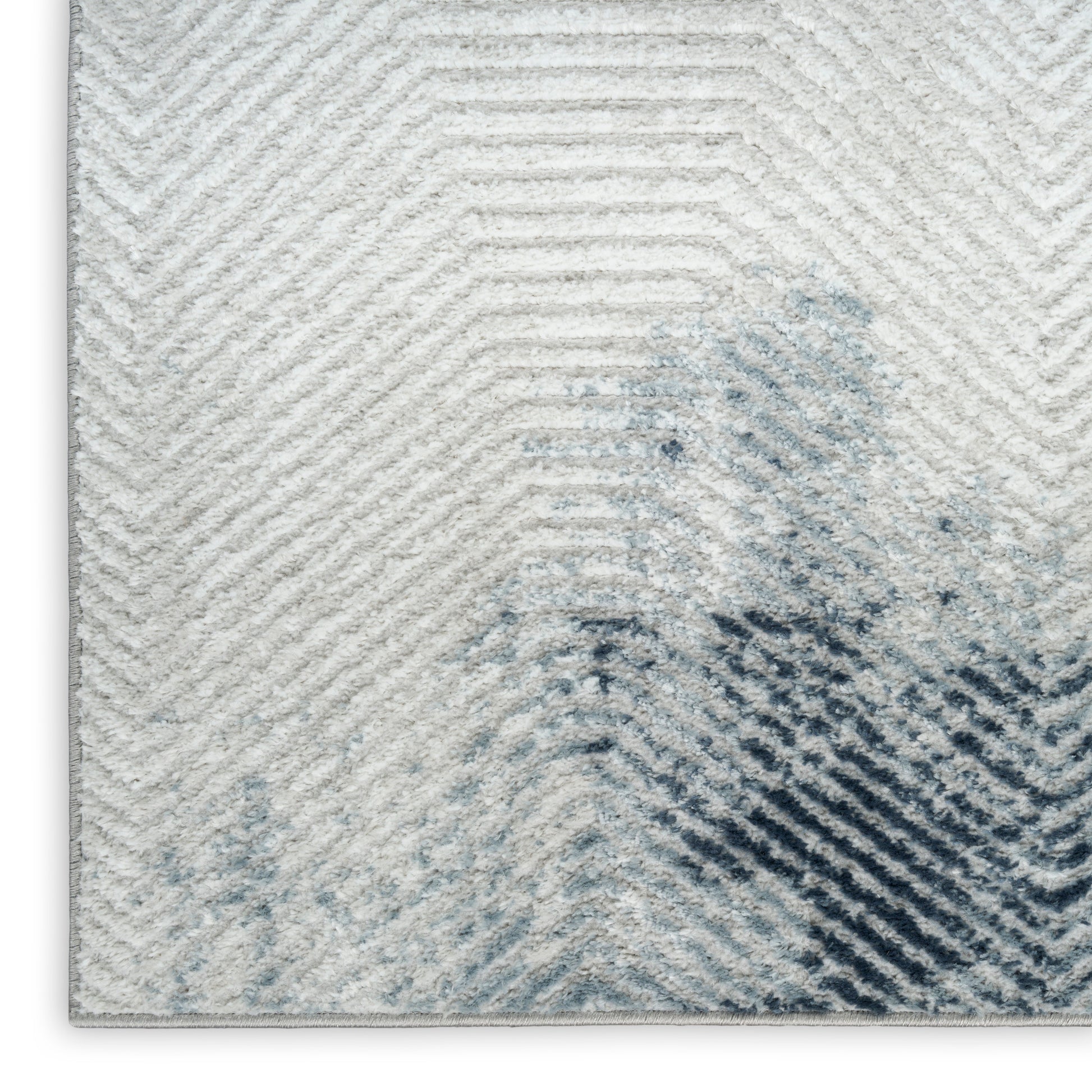 Light gray chevron rug with blue watercolor accents, plush and modern decorative floor cover.