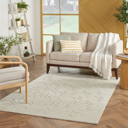 Beige fabric sofa with striped cushion and cream throw, sunlit living room with a light geometric rug and wooden furniture.
