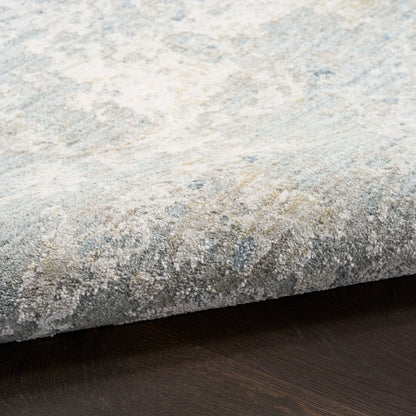 Close-up of a textured beige-blue patterned rug edge on dark wood floor.