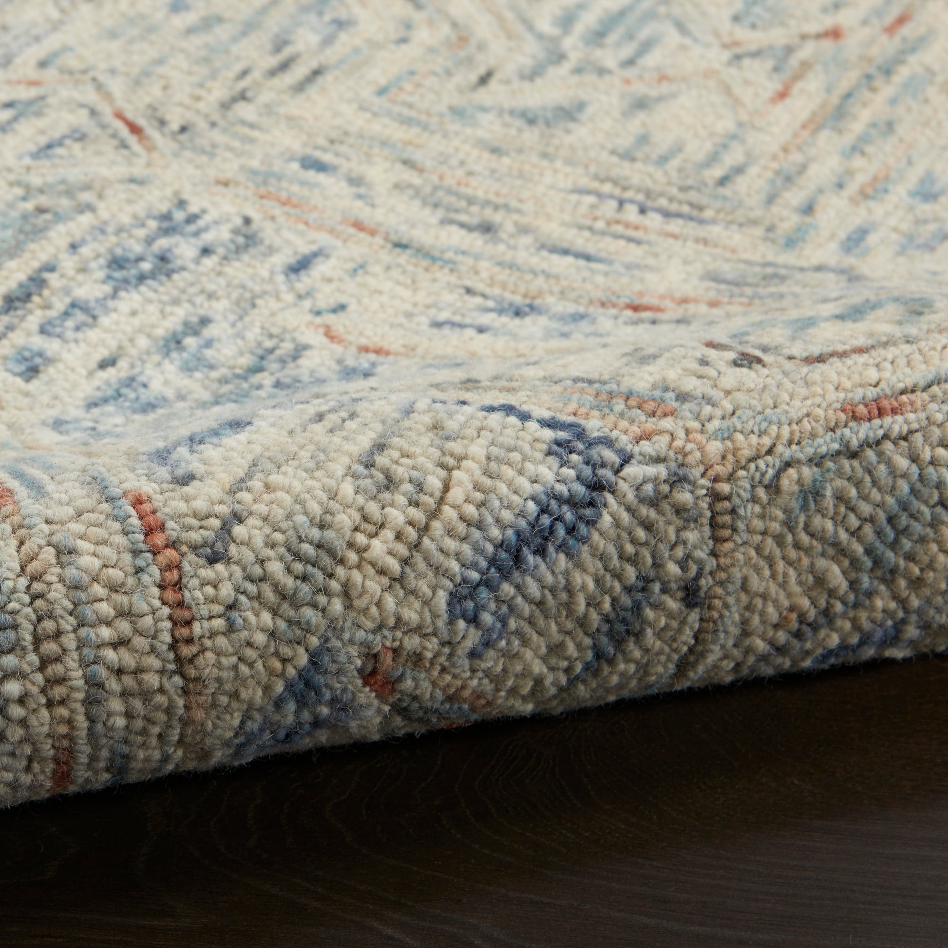 Cream textured rug with blue and orange accents; thick looped pile and woven geometric pattern.