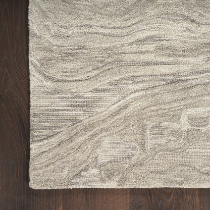 Cream-colored textured area rug with subtle wavy lines and raised floral pattern on dark wood floor.