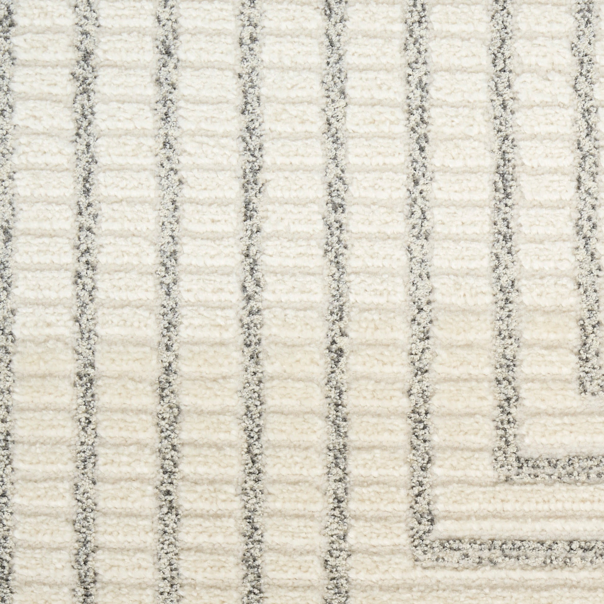 Cream rug with subtle gray vertical stripes & a bordered corner; plush loop pile.