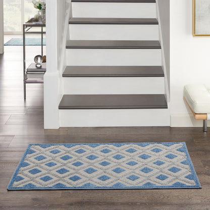 Blue and white geometric lattice rug (3' x 4') in front of a white staircase with dark wood treads on a dark wood floor.