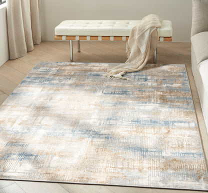 Abstract beige, blue & ivory area rug on light hardwood floor; white tufted bench with wood slats & metal legs, beige throw.