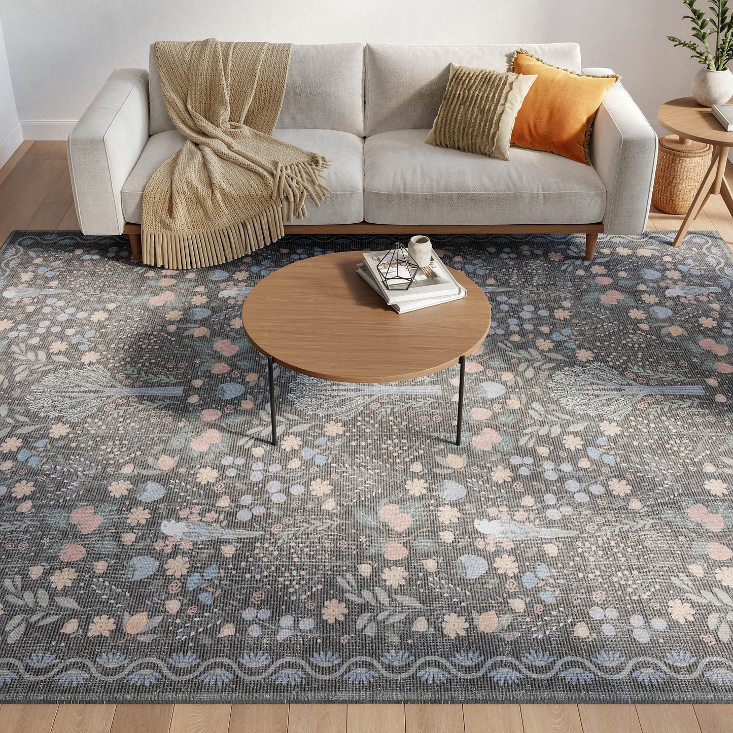 Cozy living room with gray fabric sofa, beige throw, orange cushion, round wooden coffee table on a blue floral area rug.
