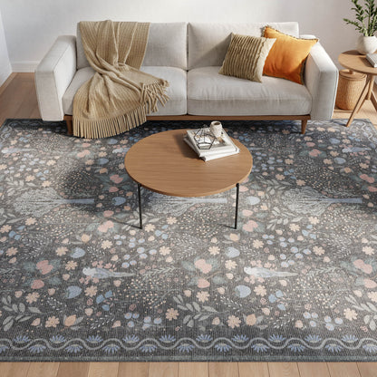 Cozy living room with gray fabric sofa, beige throw, orange cushion, round wooden coffee table on a blue floral area rug.