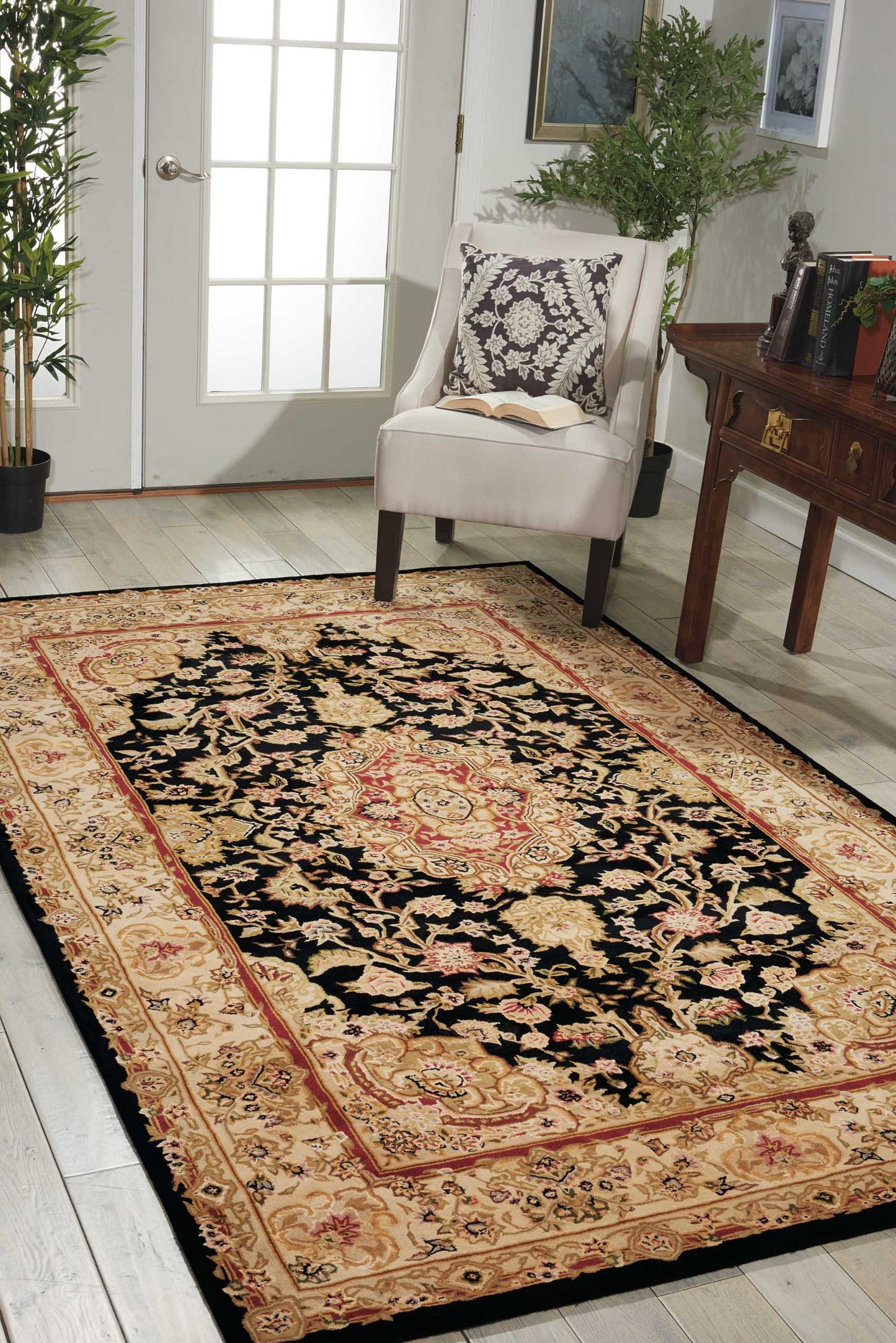 Traditional oriental rug runner with black center and red-gold floral border in a beige living room near an armchair.