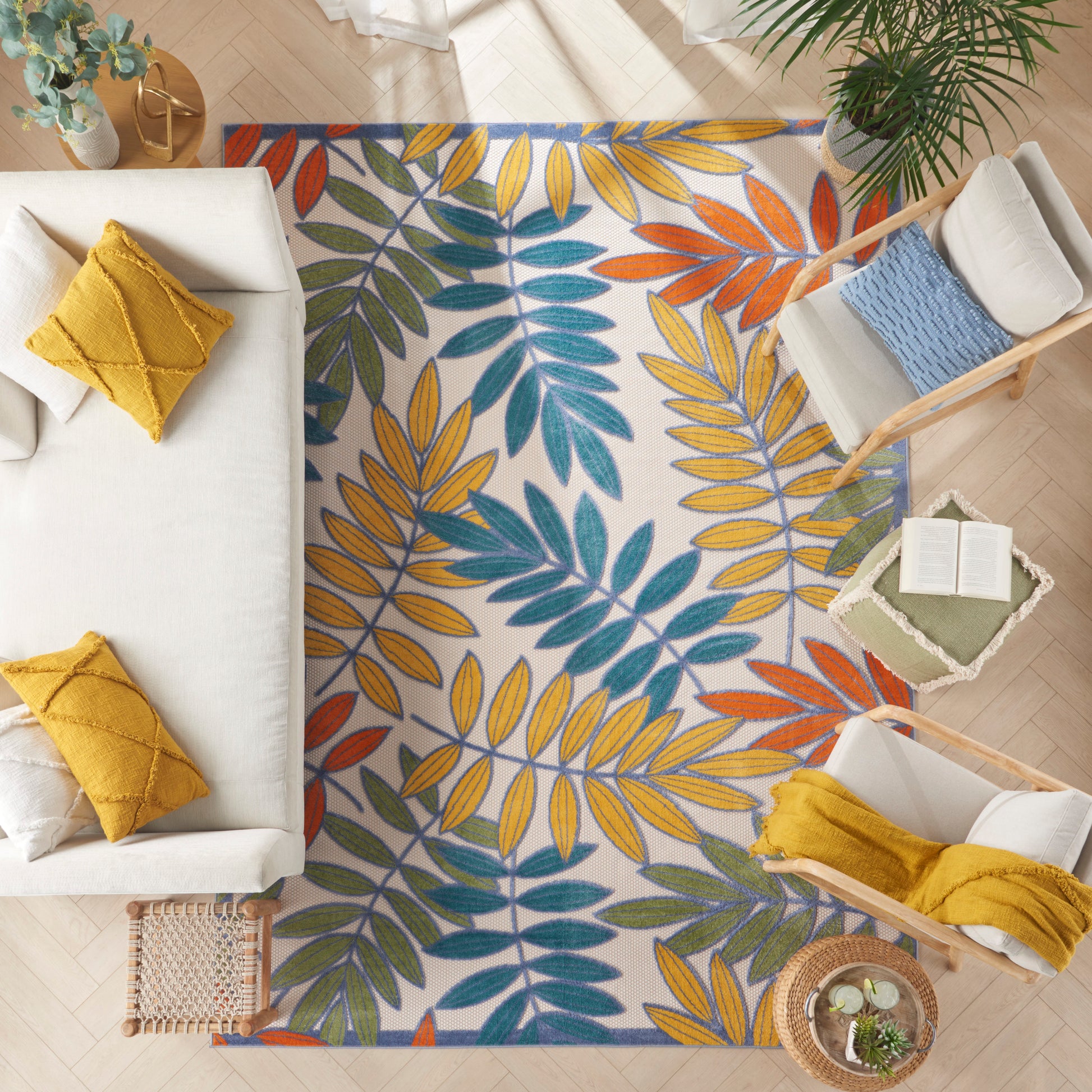 Tropical leaf rug in blue, teal, orange and yellow; white background with colorful palm fronds in a bright living room.