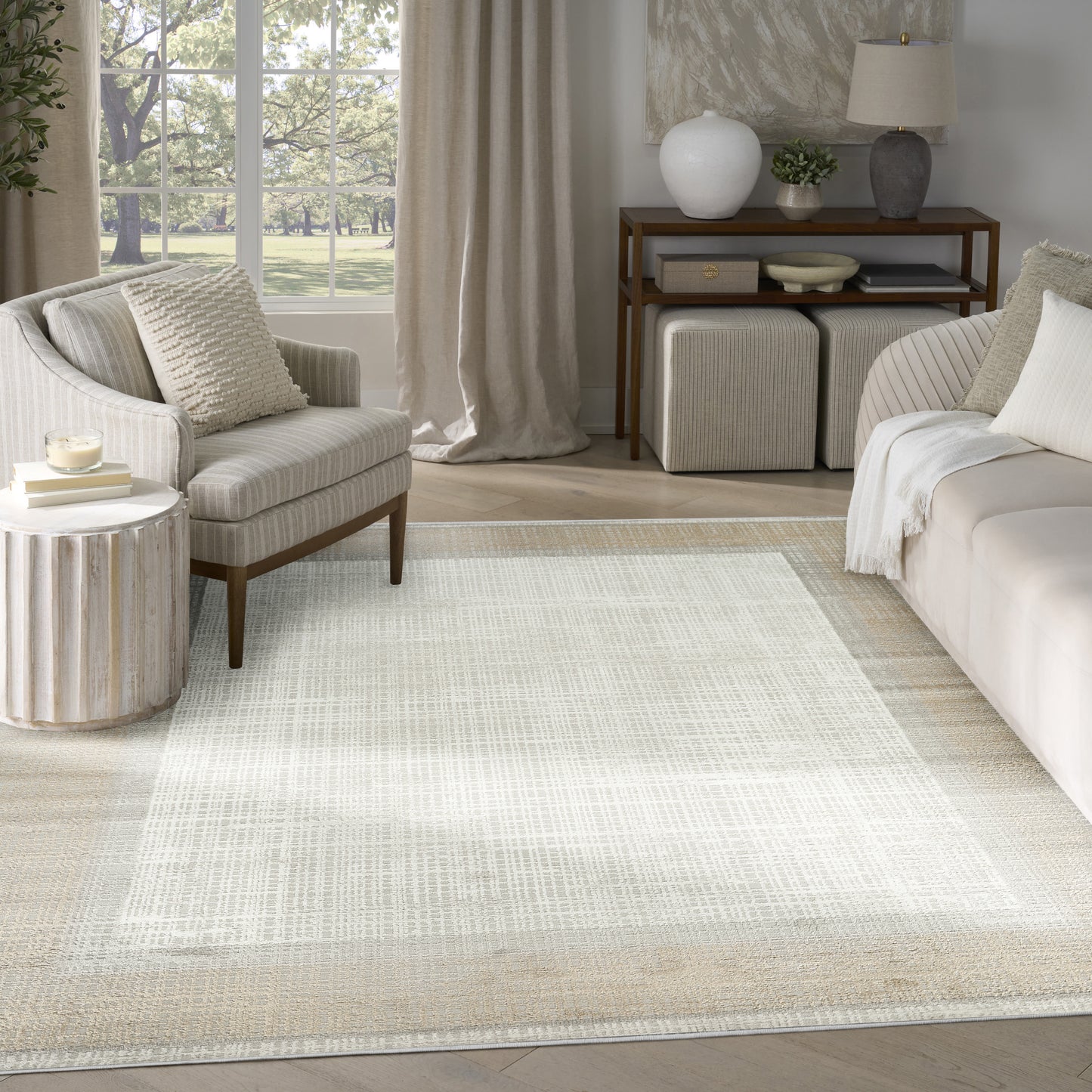 Neutral-toned living room with a large light woven area rug, cream sofa and armchair, and wooden console.