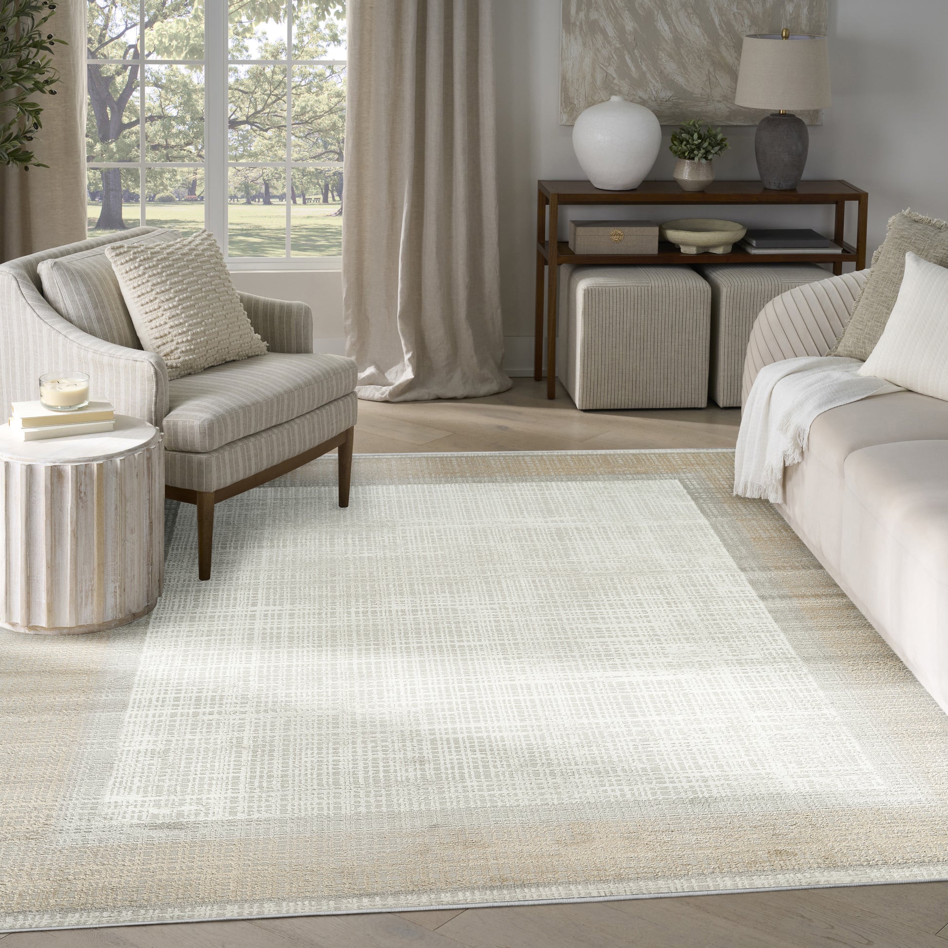 Neutral-toned living room with a large light woven area rug, cream sofa and armchair, and wooden console.