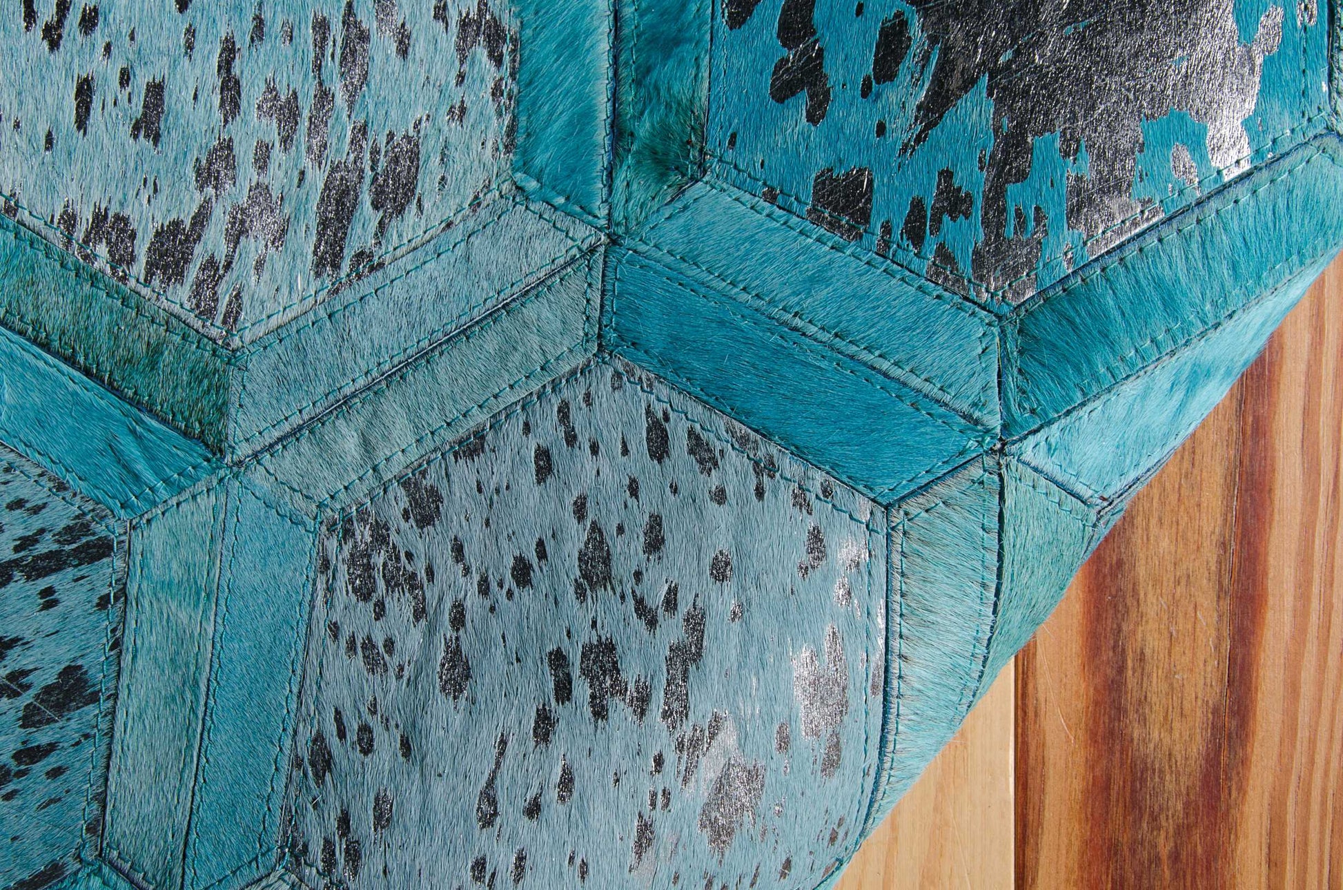 Turquoise hexagon patchwork faux leather upholstery with black speckled pattern and bold stitching.