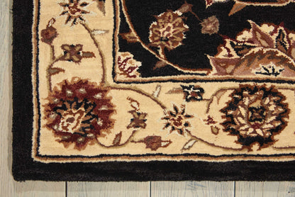 Beige oriental rug corner with black border and ornate floral motifs on a wood floor.