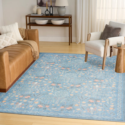 Blue floral-pattern area rug with peach accents in a Scandinavian living room; tan sofa and white armchair.