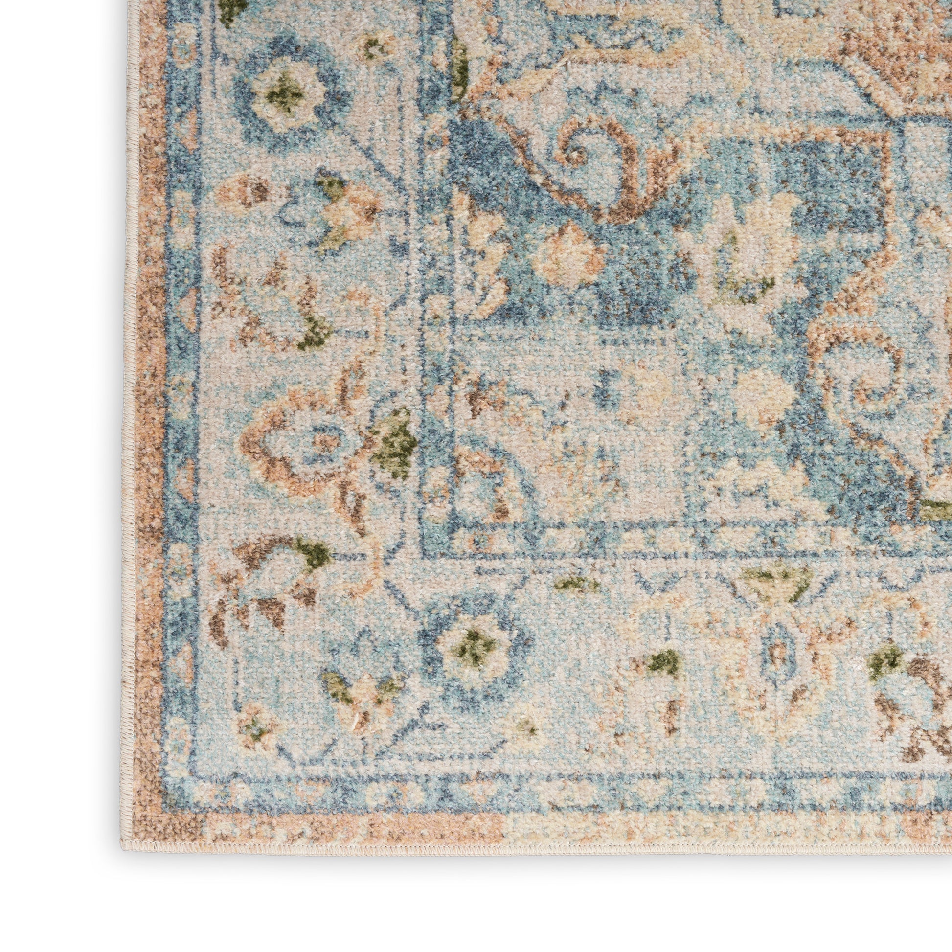 Distressed blue oriental area rug with floral motif and beige border; cropped corner shows soft pile.