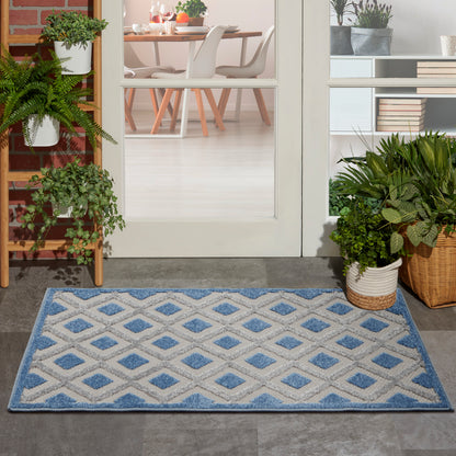 Blue and white diamond-patterned rug with a blue border in a modern glass-door entryway.