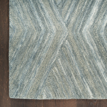 Blue & gray area rug with soft plush pile & abstract wavy chevron pattern on wood floor.