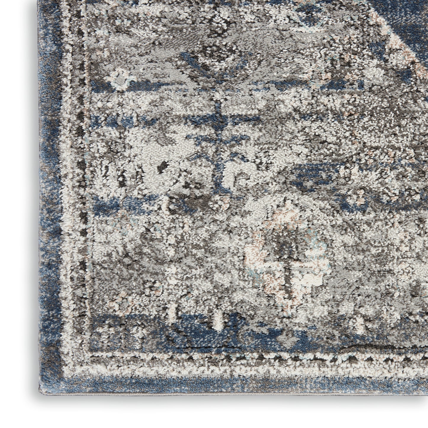 Blue-gray distressed oriental rug corner with ivory floral medallion pattern and faded border.