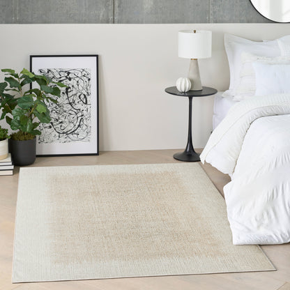 Minimalist bedroom scene with white bedding, beige natural-fiber rug, black round pedestal nightstand, white lamp, framed abstract art, and a potted plant.