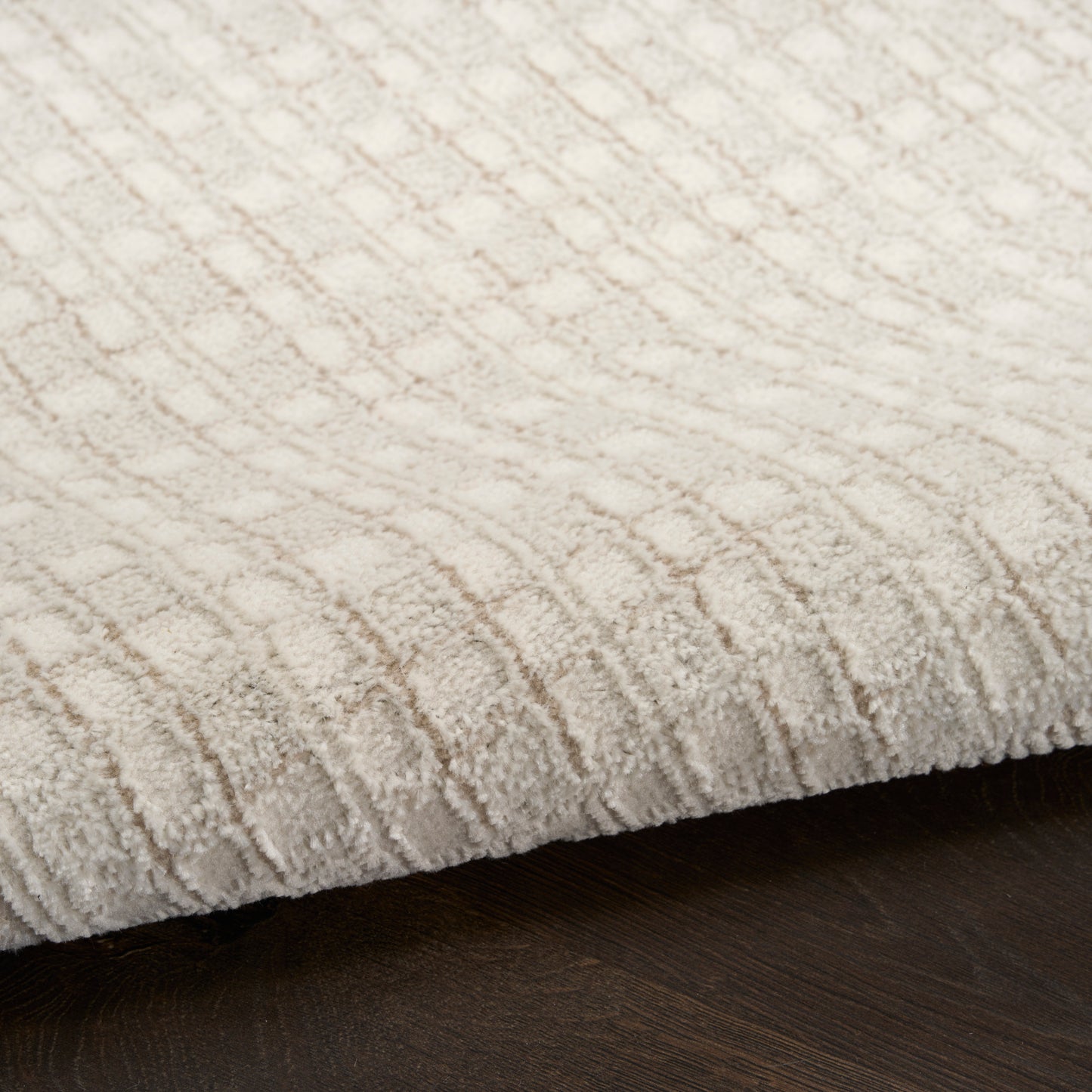 Cream textured rug with geometric diamond pattern on dark wood floor