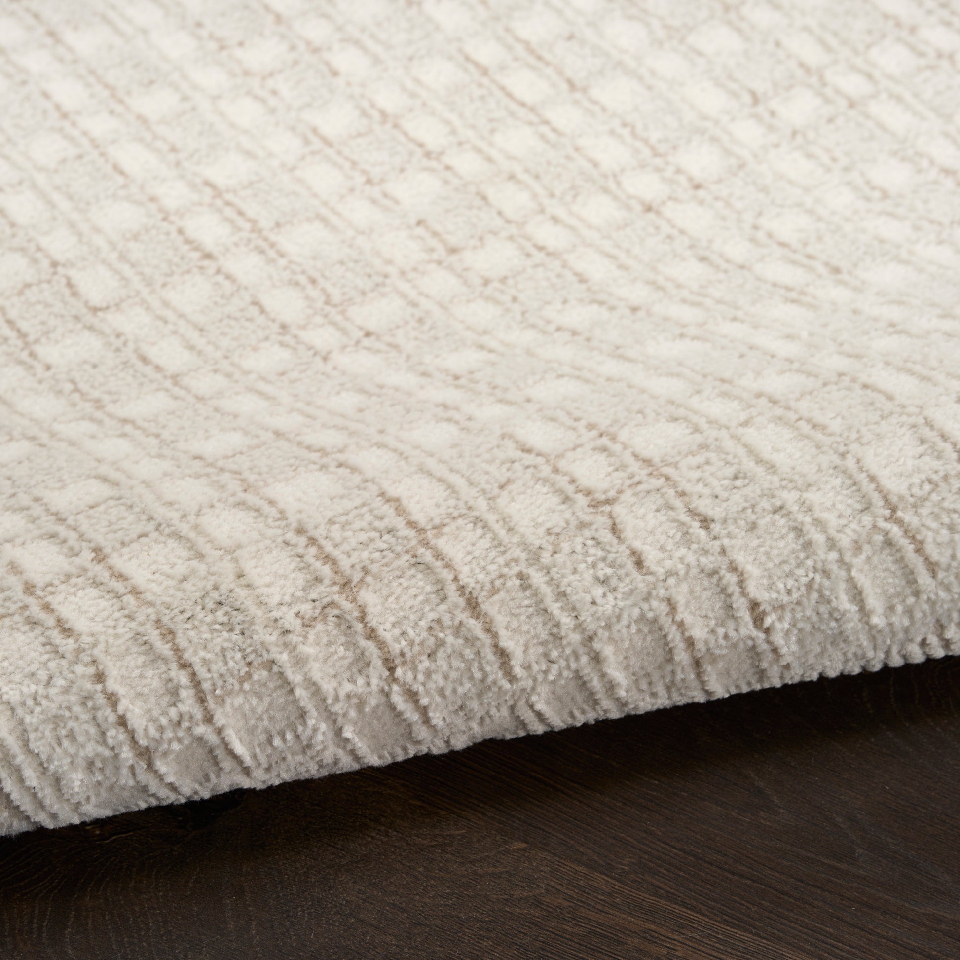 Cream textured rug with geometric diamond pattern on dark wood floor