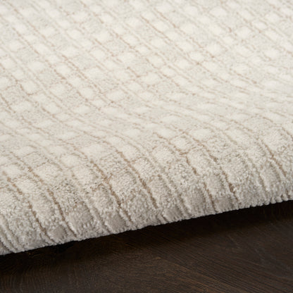 Cream textured rug with geometric diamond pattern on dark wood floor
