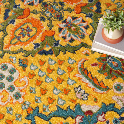 Vibrant yellow floral rug with blue, green and orange accents; corner shows a stack of books topped by a potted succulent.