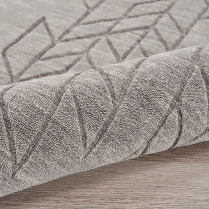 Soft grey rug with geometric diamond pattern and textured pile, rolled edge on wood floor.