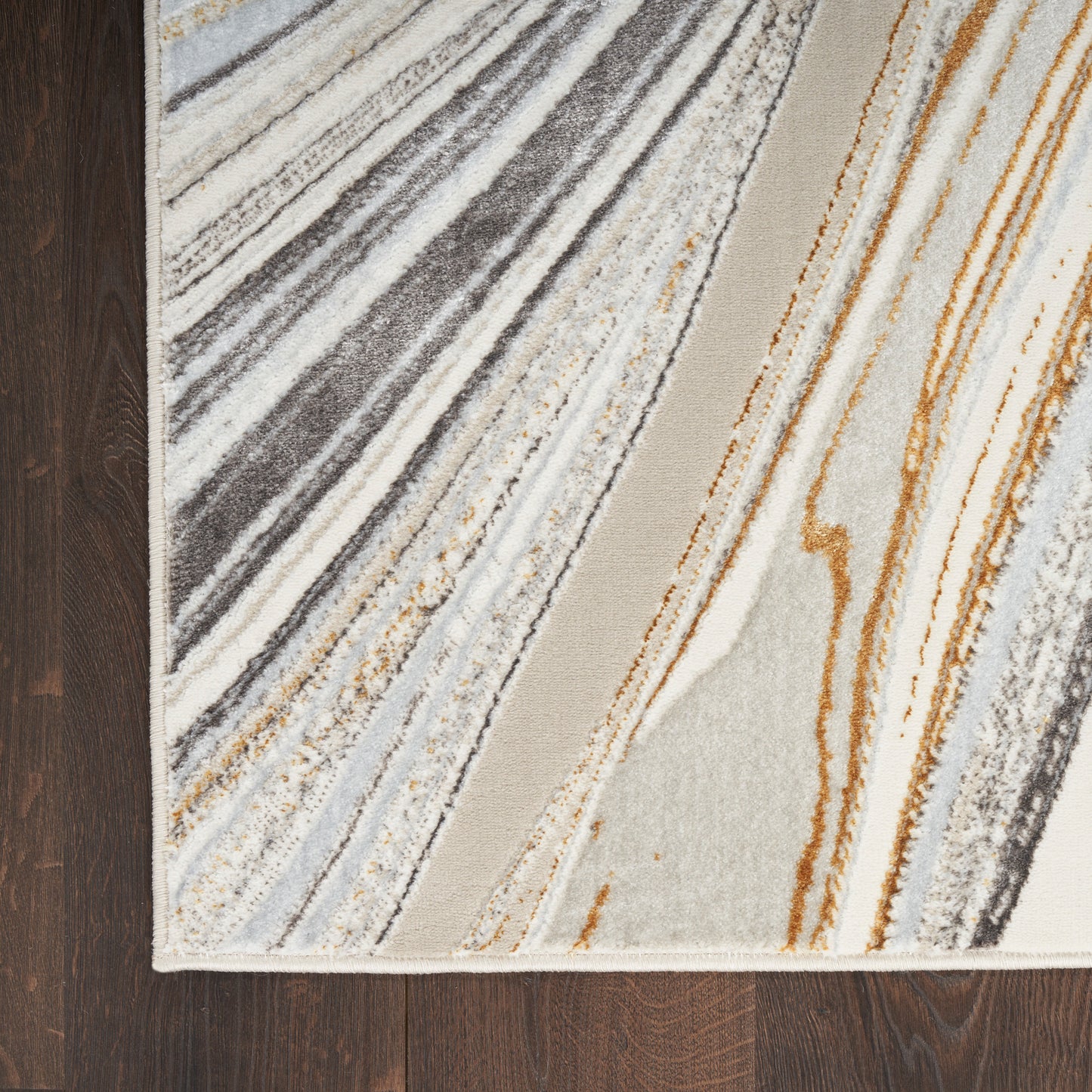 Modern abstract diagonal striped area rug in cream, gray, beige and orange on dark wood floor.