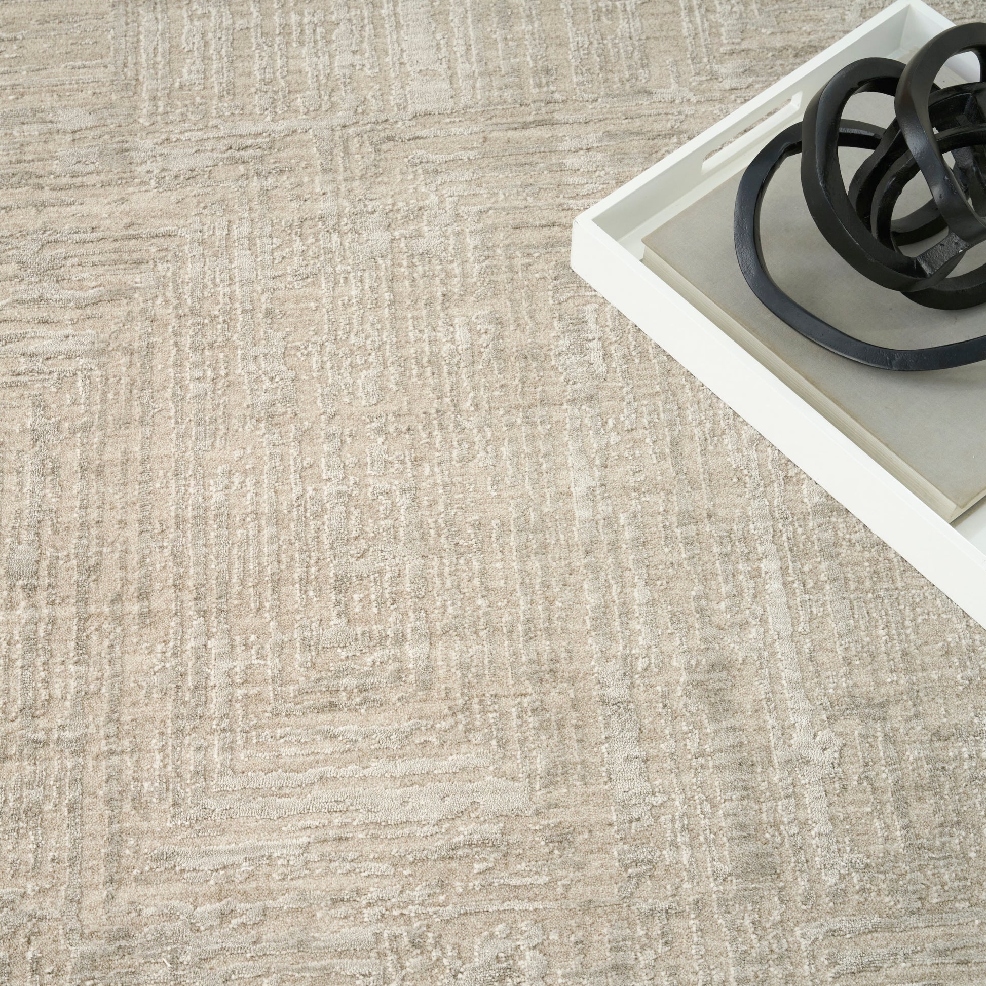 Beige textured rug with a white rectangular tray containing coiled black cords.