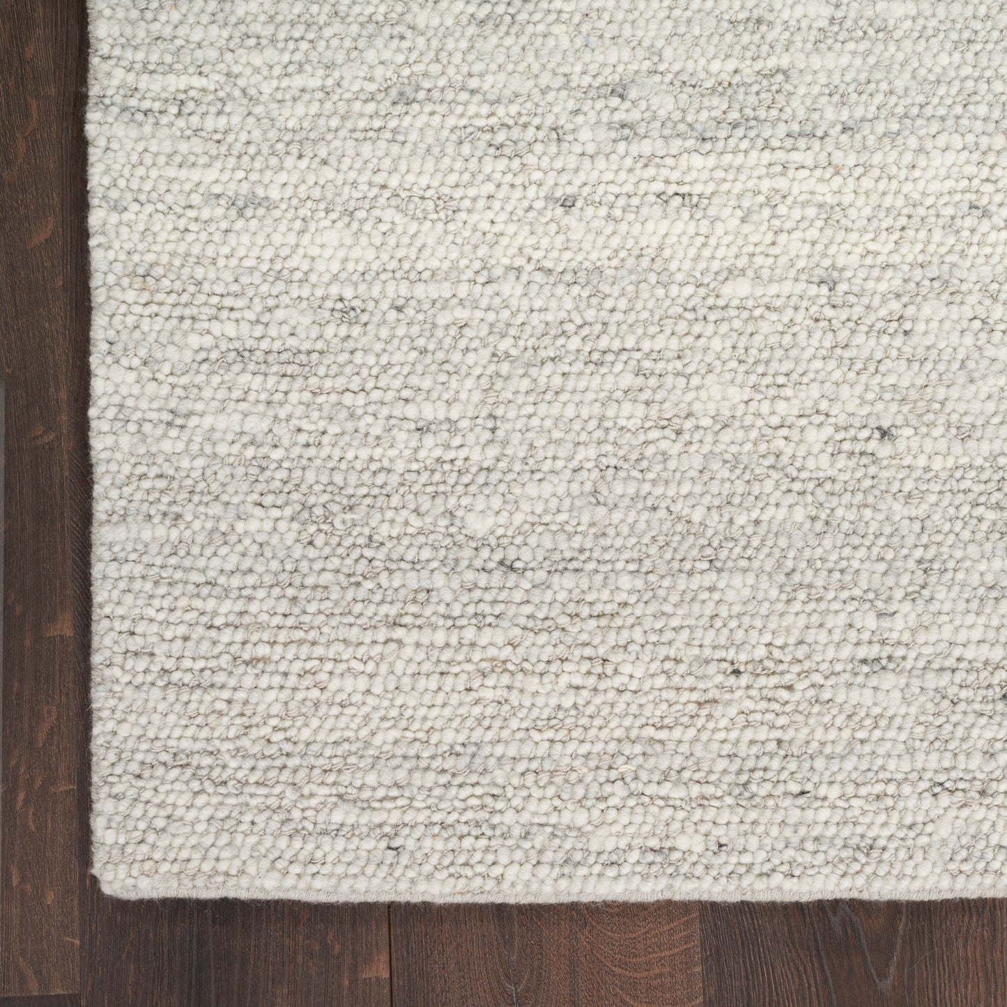 Textured cream & light gray woven rug with subtle stripes on dark wood floor.