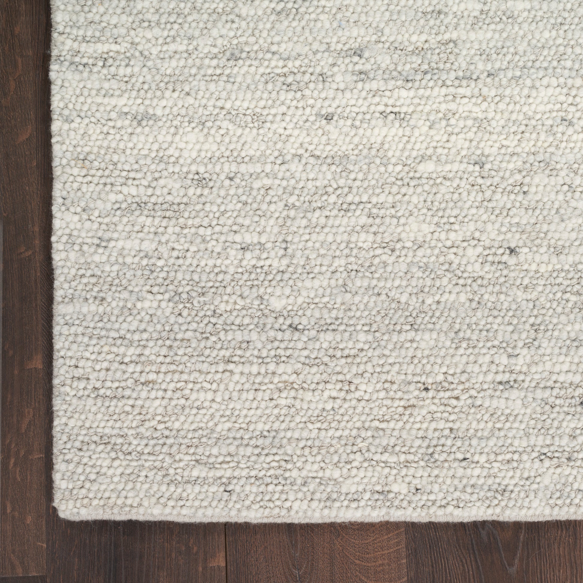 Textured cream & light gray woven rug with subtle stripes on dark wood floor.
