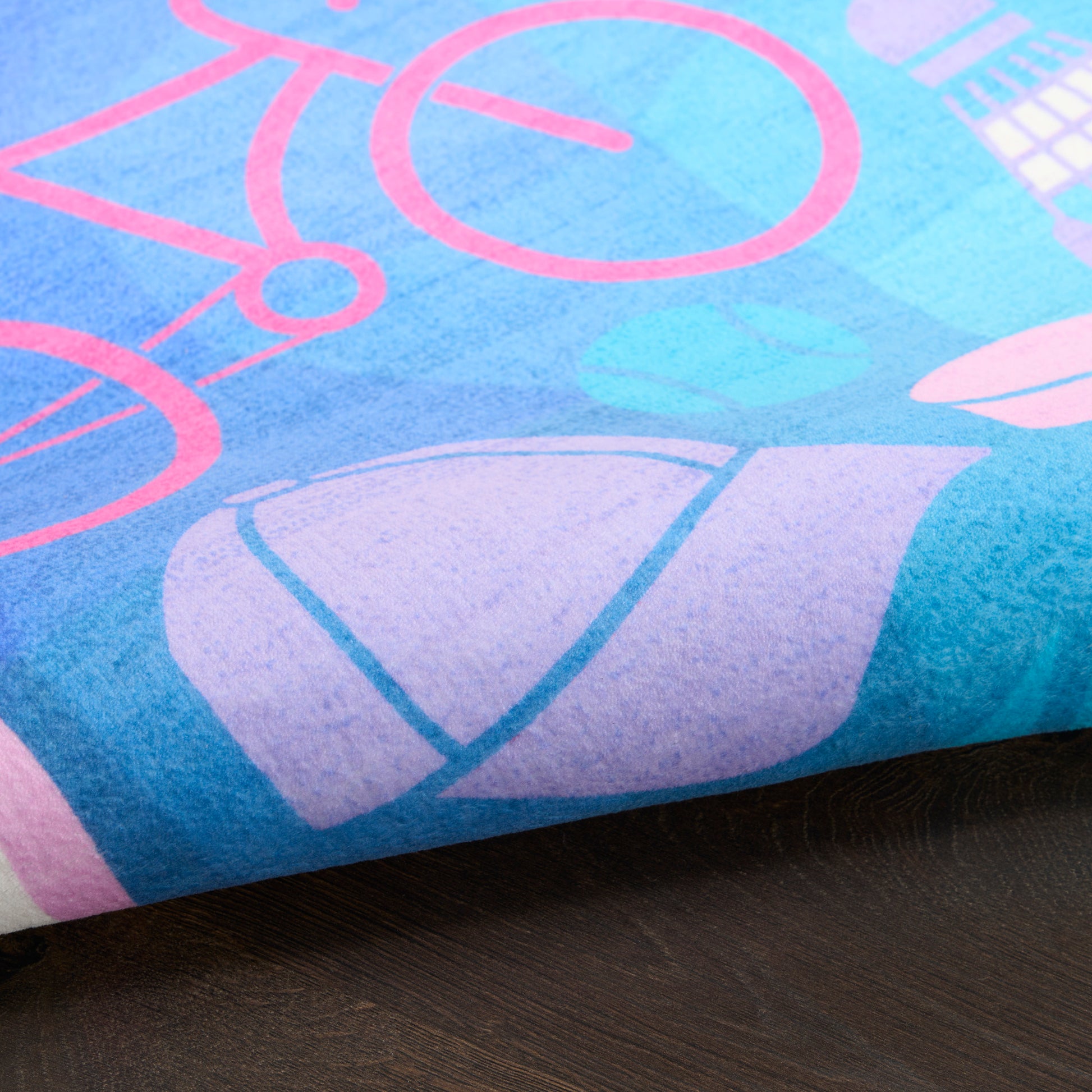 Blue kids' rug with pink bicycle graphic and purple shapes, rolled edges, 4' x 6