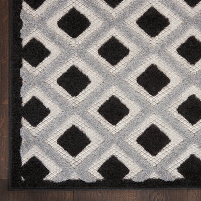 Gray modern rug on dark wood floor with a black-and-white geometric pattern.