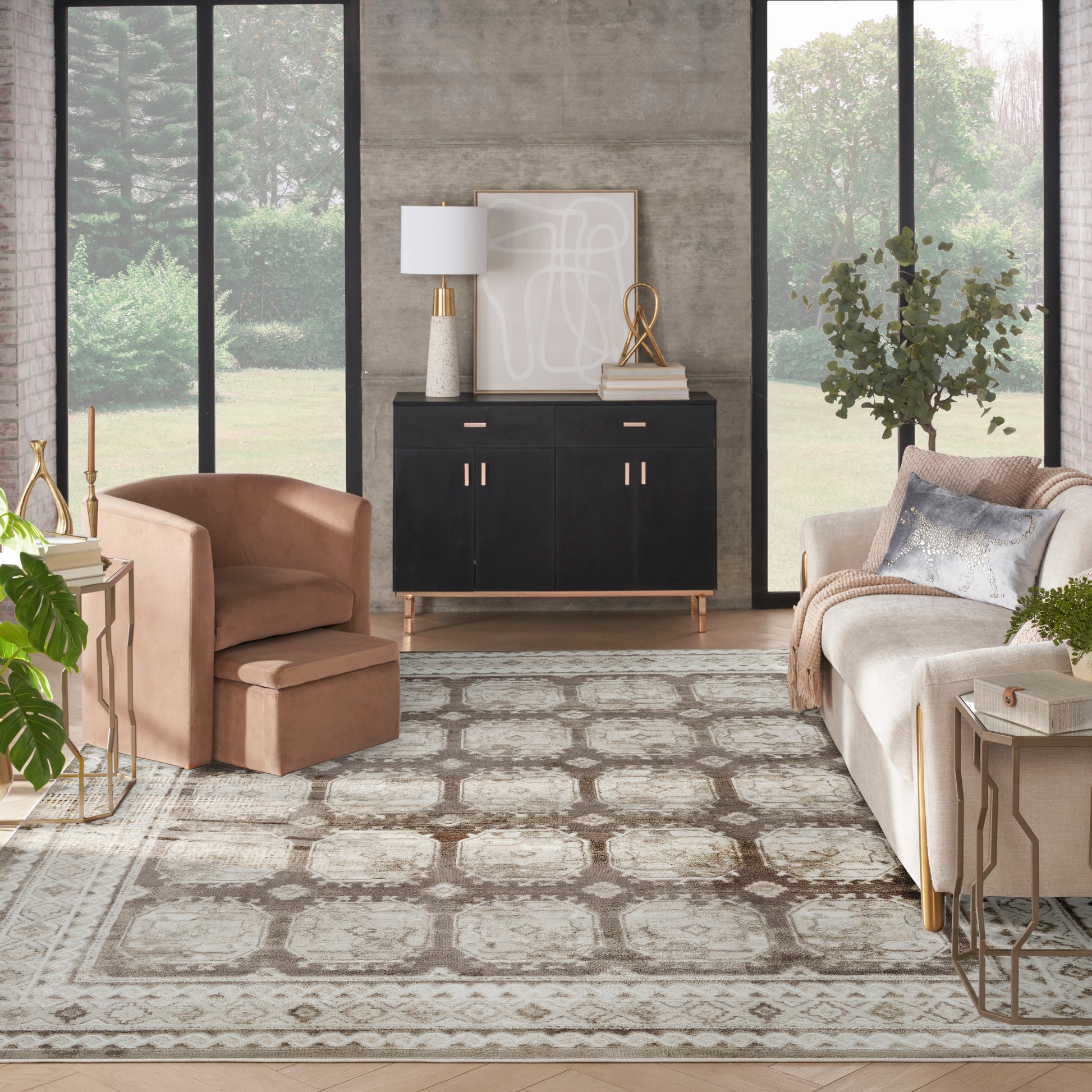 Contemporary living room with beige sofa, blush armchair, black sideboard with gold handles, cream patterned rug, large windows.