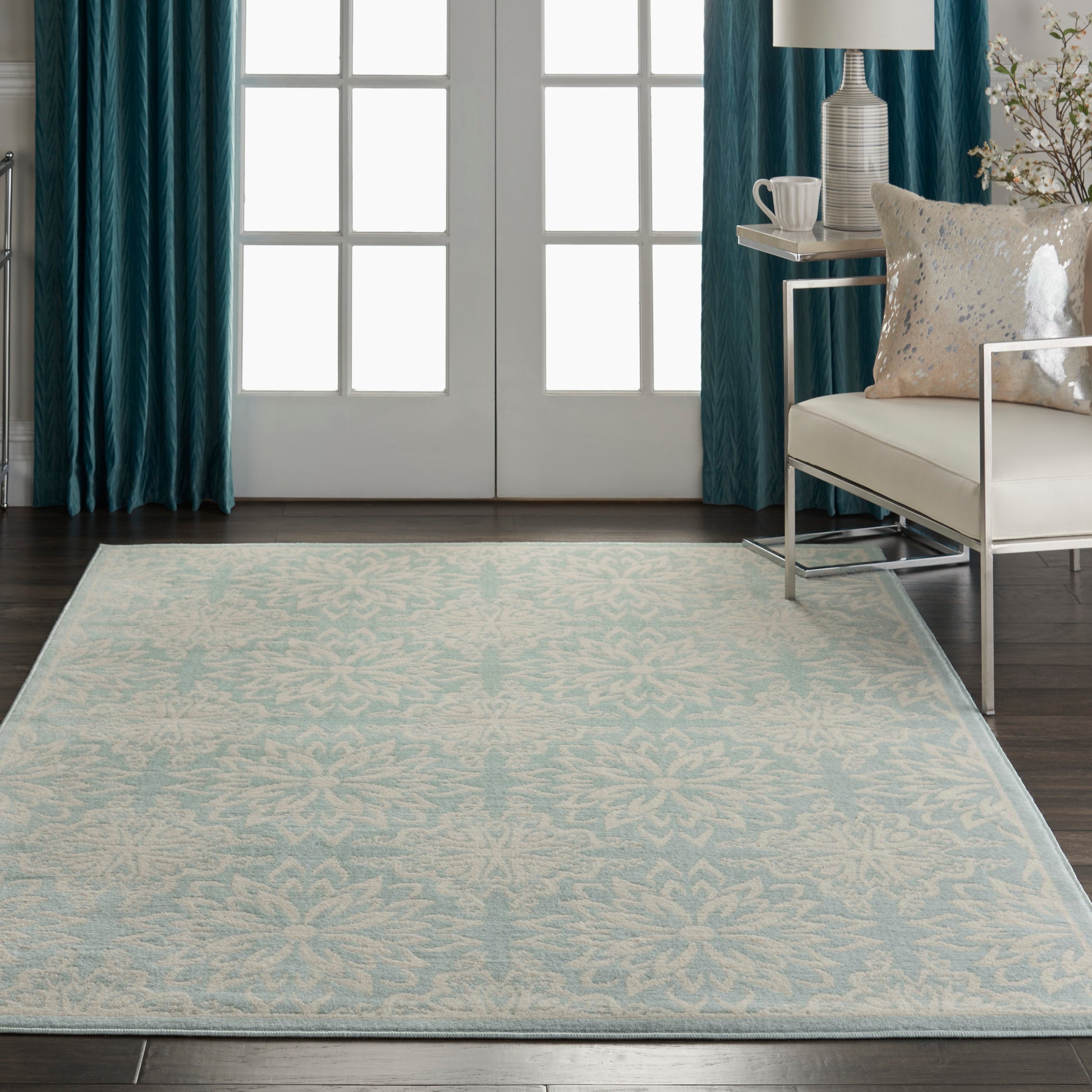 Light blue patterned area rug with delicate white motif, in modern living room with teal curtains and white sofa.