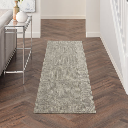 Long beige-gray geometric textured runner rug on dark herringbone hallway floor beside a chrome console table.
