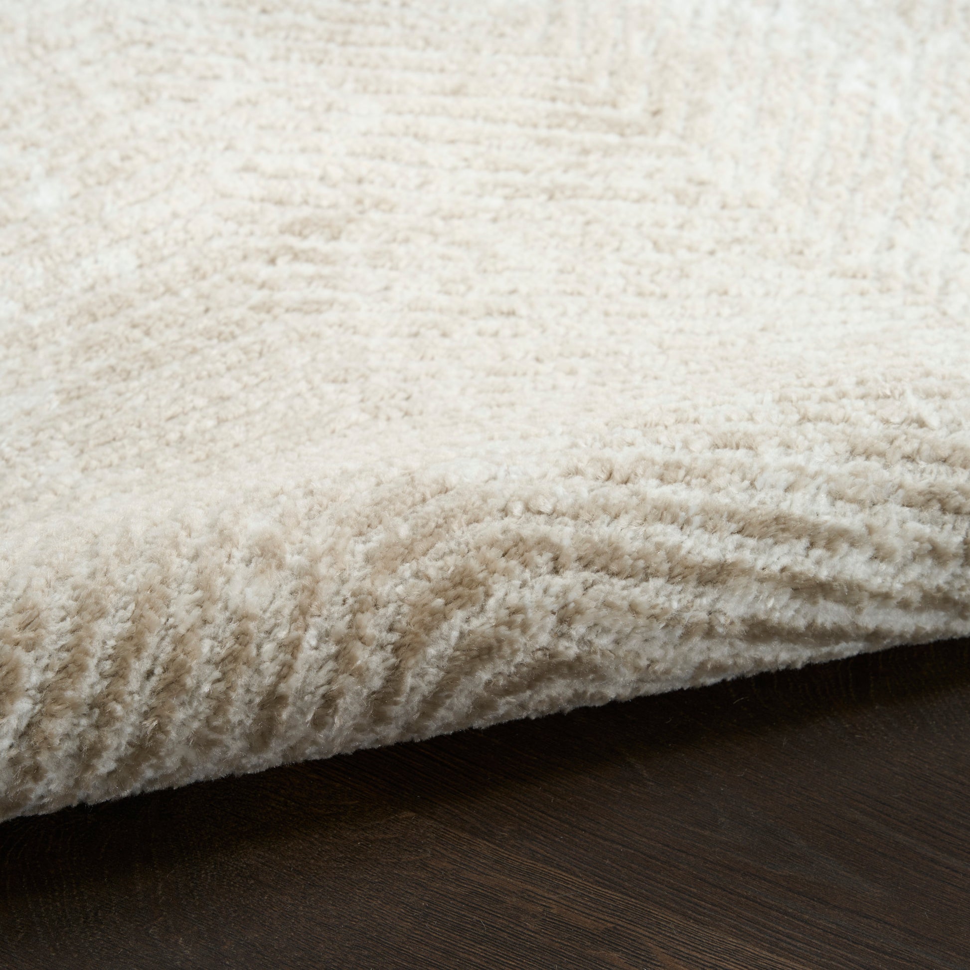 Cream shag rug with thick, plush pile laid on dark wooden floor.